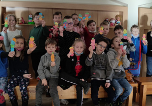 Uczniowie z klasy 2 c prezentują do obiektywu bałwanki wykonane z kolorowych opłatków w kształcie kół.