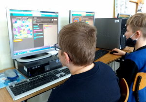 Chłopcy kodują ruch postaci na ekranie za pomocą kodu blokowego.