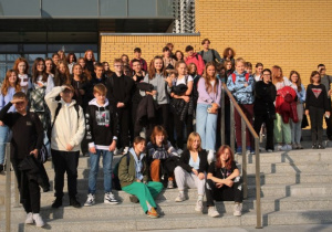 Uczniowie Szkoły Podstawowej nr 12 stoją na schodach budynku Uniwersytetu i pozują do zdjęcia.
