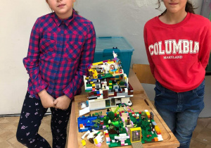 Dwie uczennice prezentują swoją pracę - makietę wykonaną z klocków lego.