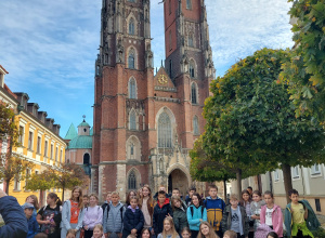 Uczestnicy wycieczki, uczniowie klasy 5a i 5e stoją przed katedrą na rynku we Wrocławiu.