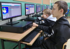 Uczniowie 8 klasy pracują przy komputerach. Chłopcy z klasy 8 a kodują w języku Scratch według samouczków.