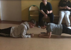 Uczniowie bawią się w przerwach między seansami filmowymi. Chłopcy wykonują podpór przodem na podłodze.