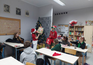 Uczennice (jedna przebrana za renifera, druga w stroju elfa) rozdają przygotowane prezenty.
