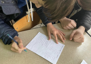 Uczniowie czytają i rozwiązują zadania zapisane na kartce
