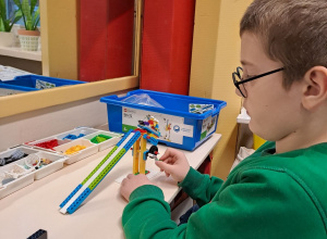 Uczeń testuje tor saneczkowy zbudowany z klocków Lego.