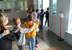 Uczniowie tworzą pociąg i idą korytarzem do biblioteki szkolnej.