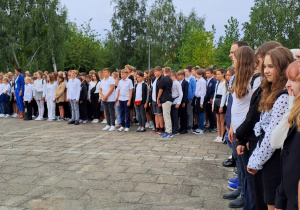 Uczniowie stoją na placu apelowym przed szkołą.