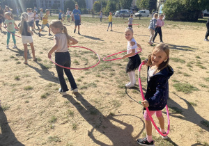 Uczniowie bawią się z hula hop na boisku szkolnym.