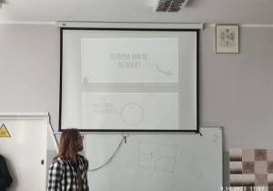 Uczeń stoi przed ekranem projektora i opowiada o nowych zawodach.