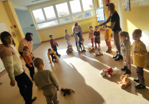 Grupa przedszkolaków stoi w kole i uczestniczy w zabawie.