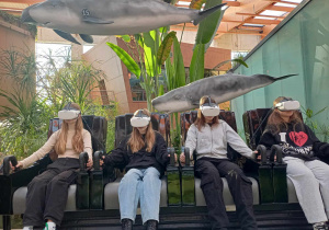 Uczennice siedzą w fotelach, na oczach mają gogle wirtualne rzeczywistości.
