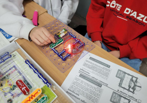 Uczeń włączył zbudowany model. W zestawie elektronicznym świeci się żarówka i kręci się śmigło.