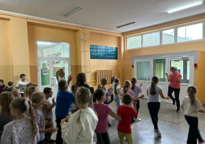 Uczniowie tańczą zumbę według kroków pokazywanych przez nauczycielkę.