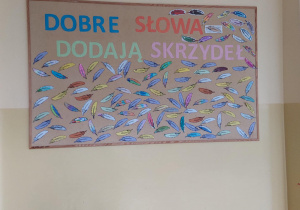 Na tablicy korkowej znajdują się kolorowe piórka z miłymi słowami.