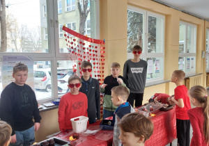 Uczniowie w okularach w kształcie serca sprzedają walentynkowe muffinki.