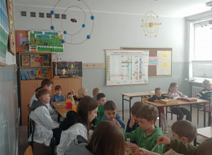 Uczniowie siedzą w ławkach, znajdują się w sali od chemii.