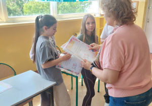 Nauczyciel wręczadyplomy za udział uczestnikom.