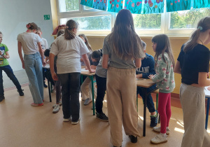 Uczniowie, każdy prz swoim stanowisku dyktuje zapamiętany tekst dyktanda osobie, która zapisuje wszystko na kartce.