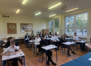 Uczniowie siedzą w ławkach, przed rozpoczęciem egzaminu.