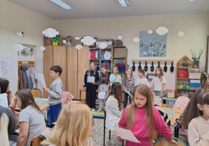 Uczniowie i rodzice siedzą przy stolikach i wykonują wspólnie zadania.