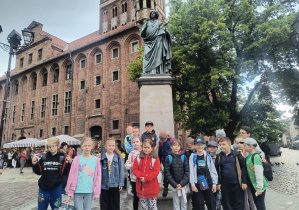 Uczniowie stoją przy pomniku Mikołaja Kopernika