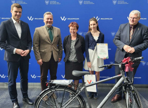 Uczennica z nauczycielką i organizatorami ze zdobytą nagrodą - rower.
