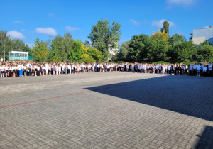 Uczniowie wszystkich klas ustawieni na palcu przy szkole.