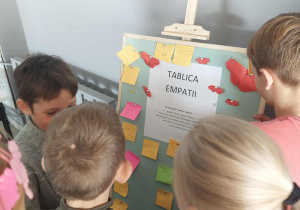 Uczniowie stoją przy tablicy, przyklejają kolorowe kartki z napisami.