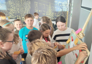 Uczniowie stoją przy tablicy, przyklejają kolorowe kartki z napisami.