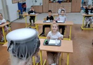Dzieci w klasie przyglądają się esperamentom z suchym lodem