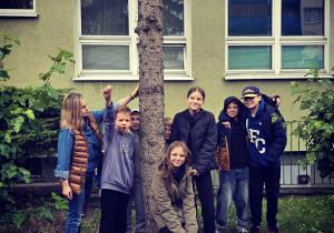 Uczniowie podczas zajęć plenerowych tulą się do drzewa.