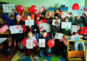 Uczniowie z czerwonymi balonami gotowi do marszu przeciwko przemocy wobec dzieci.